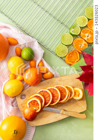 Citrus fruits are being prepared for Christmas drying. Different types of citrus are placed on a cutting board and drying rack in a home kitchen. The scene shows a festive activity Citrus fruits are being prepared for Christmas drying. Different types of citrus are placed on a cutting board and drying rack in a home kitchen. The scene shows a festive activity 143826023