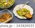 Quinoa with green peas, arugula, cauliflower, and broccoli is served with liver pate on a plate at a table during breakfast 143826035