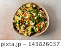 Baked chicken breast is mixed with chopped carrots, broccoli, cauliflower, and fresh herbs in a bowl. This dish is ideal for a nutritious breakfast or lunch meal 143826037
