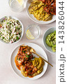 Plates hold amaranth, millet, and quinoa porridge served with baked white hake in tomato sauce. Fresh salad is beside the porridge. A bowl of kiwi sits nearby for dessert 143826044