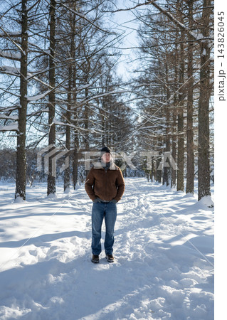 Young man standing on snowy path in winter forest Young man standing on snowy path in winter forest 143826045