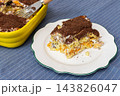 A slice of homemade gluten-free tiramisu cake with savoiardi ladyfingers and chocolate crumbs rests on a plate on a wooden table indoors 143826047
