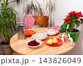 A table is set with bowls of ingredients for Olivier salad. There are vegetables like carrots, potatoes, and beets ready for mixing. Decorations add a festive touch 143826049