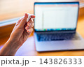 Woman squeezing stress relief putty while working at laptop. Sensory hand exercise helps reduce tension and manage stress during computer work 143826333