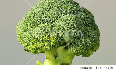 Close up of fresh broccoli with water droplets on green florets and a neutral background, shot at eye level. Healthy eating and clean produce support nutrition, vegan meals, and home cooking. 143827316