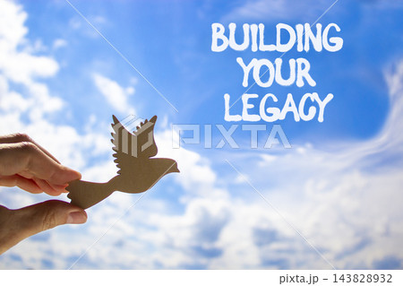 Building your legacy words symbol. Concept words Building your legacy on beautiful blue sky. Beautiful blue sky background. Businessman hand. Business building your legacy concept. Copy space. Building your legacy words symbol. Concept words Building your legacy on beautiful blue sky. Beautiful blue sky background. Businessman hand. Business building your legacy concept. Copy space. 143828932