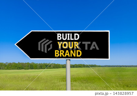 Build your brand words symbol. Concept words Build your brand on beautiful black road sign. Beautiful blue sky green grass background. Business and build your brand concept. Copy space. 143828957
