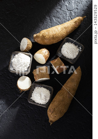 pile of cassava and cassava flour on dark background (Manihot esculenta) 143829529