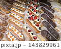 Delicious collection of colorful eclairs in a bakery display case 143829961