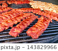 Savoring perfectly grilled ribs and chicken at a summer barbecue gathering 143829966