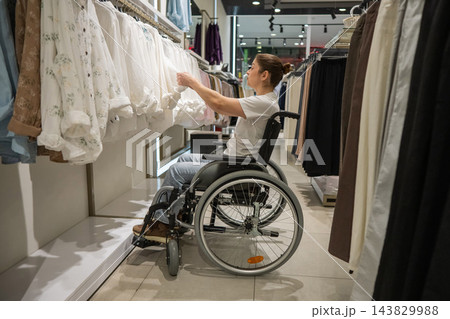 A Caucasian woman in a wheelchair shopping at a mall.  143829988