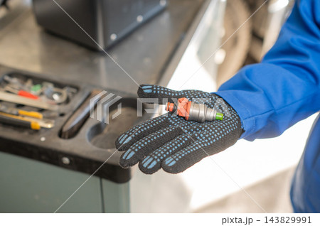 A mechanic is holding a car fuel injector. 143829991