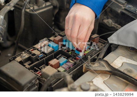 A woman removes a fuse from the car. 143829994