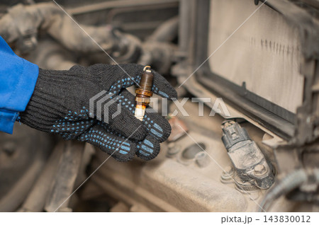A mechanic is changing the spark plugs in a car. A mechanic is changing the spark plugs in a car. 143830012