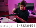 Portrait of young man performing maintenance on electronic keyboard using small vacuum cleaner, ensuring optimal performance and longevity for computer equipment. 143830454