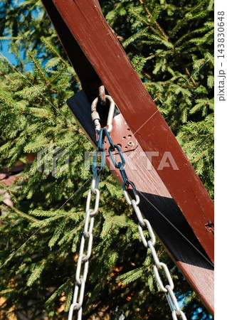 Metal chain attached to a brown wooden beam at a park during the day Metal chain attached to a brown wooden beam at a park during the day 143830648