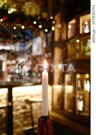 Glowing candle illuminating a cozy winter pub interior at night 143830701