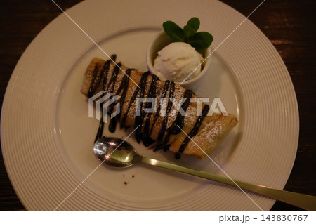 Warm apple strudel drizzled with chocolate sauce and vanilla ice cream 143830767