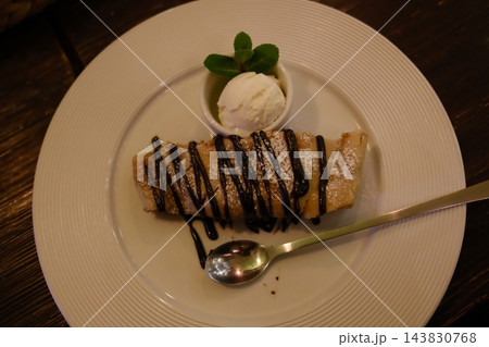 Warm apple strudel drizzled with dark chocolate sauce and vanilla ice Warm apple strudel drizzled with dark chocolate sauce and vanilla ice 143830768