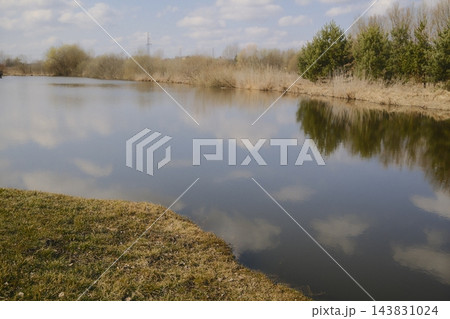 Still water perfectly mirrors a blue sky with fluffy white clouds Still water perfectly mirrors a blue sky with fluffy white clouds 143831024