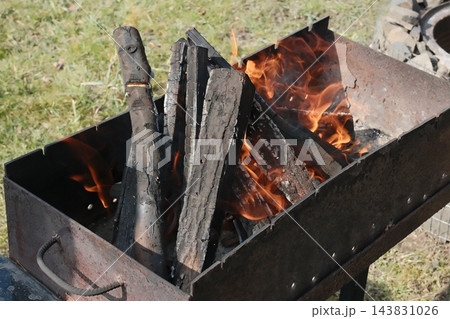Wooden logs are actively burning in a metal brazier, generating heat 143831026