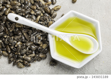castor oil seeds spoon and white bowl, top view 143831189