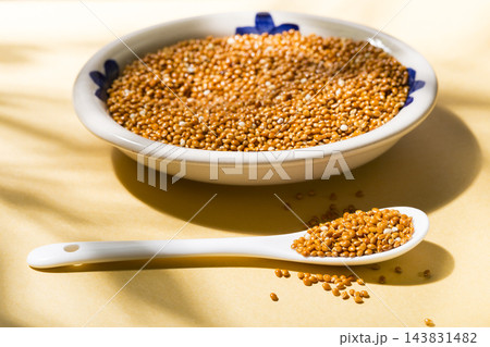 healthy grains of red millet served in a plate on yellow background 143831482