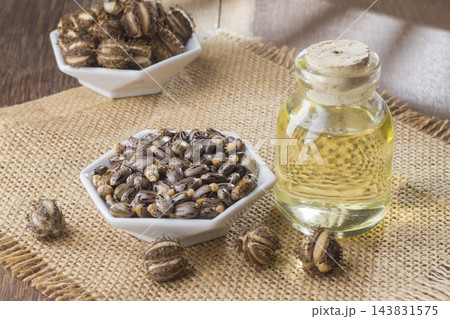seeds and castor oil on the wooden table - Ricinus communis seeds and castor oil on the wooden table - Ricinus communis 143831575