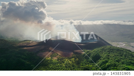 Aerial view Mount Yasur, an active stratovolcano on Tanna Island, Vanuatu, continuously emits white smoke and ash from its crater, creating a dramatic natural landscape of lush tropical vegetation Aerial view Mount Yasur, an active stratovolcano on Tanna Island, Vanuatu, continuously emits white smoke and ash from its crater, creating a dramatic natural landscape of lush tropical vegetation 143831905