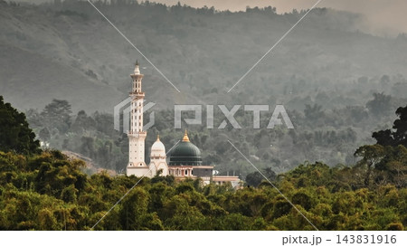 Sembalun mosque standing prominently with its tall minaret and green dome, surrounded by lush rainforest trees and misty mountains, capturing the serene and spiritual landscape of Lombok 143831916