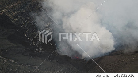 Mount Yasur crater belching thick white and gray smoke while glowing magma lights the vent, dramatic volcanic power on Tanna Island, Vanuatu, raw and explosive landscape. Aerial view drone shot 143832016