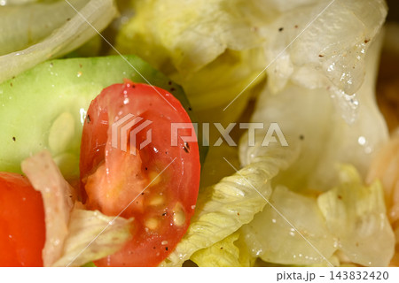 A detailed close-up photograph of a freshly prepared salad with vibrant red tomatoes 143832420