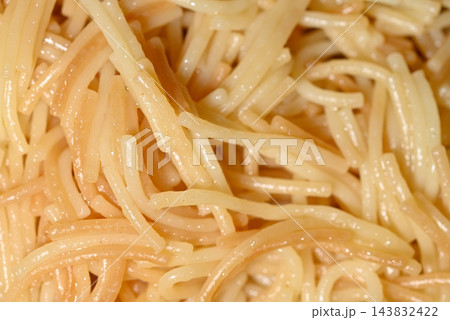 A close-up macro photograph showing a pile of light-colored spaghetti strands, likely creamy and interwoven with gentle curves and slight bends 143832422