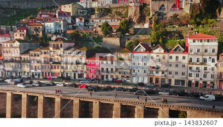 Porto historic Ribeira district with colorful traditional houses buildings and hillside architecture, with people walking on the riverfront promenade along the Douro River in Portugal. Panoramic shot 143832607