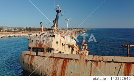 The Edro III shipwreck, a rusty cargo vessel stranded along the Mediterranean coastline near Peyia, Cyprus, becoming a significant landmark and tourist attraction. Aerial view drone zoom out flight 143832646
