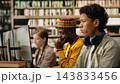 Student, headphones and computer as young man focuses on desktop monitor while classmates work nearby in library. Digital literacy, independent study and academic focus support computer learning. 143833456