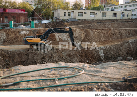 Excavator working in deep foundation pit at urban construction site Excavator working in deep foundation pit at urban construction site 143833478
