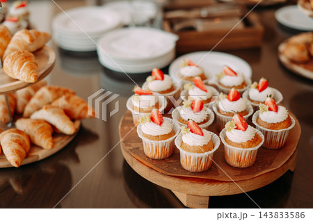 Strawberry cupcakes with whipped cream on a dessert buffet with fresh croissants 143833586