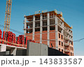 Multi-story building under construction with tower crane and concrete frame 143833587