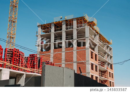 Multi-story building under construction with tower crane and concrete frame 143833587
