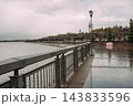 Rainy waterfront promenade with wet pavement and metal railing on an overcast day 143833596