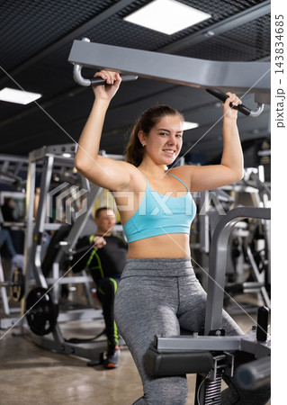 Young female training trains the muscles of the arms and press on simulator in gym. Sport concept 143834685