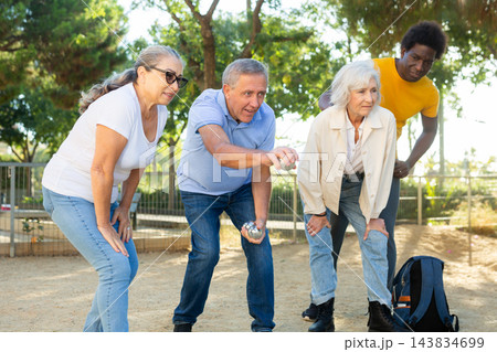 Positive multiracial mature people playing petanque game outdoors in autumn 143834699