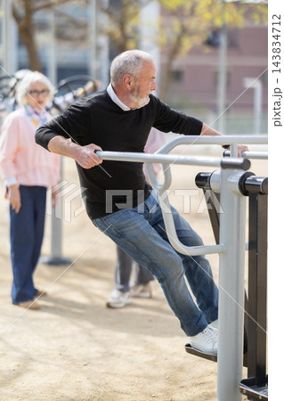 Senior man training on outdoor gym equipment Senior man training on outdoor gym equipment 143834712