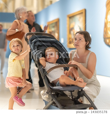 Woman with two children walk around museum hall 143835178