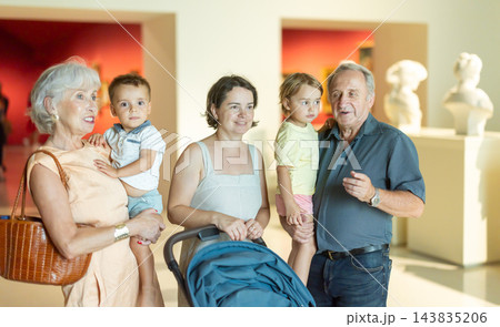 Multi-generation family observing artwork in gallery with sculptures in background 143835206