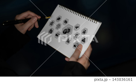 Hand holding sketchbook with various icons and symbols representing business, travel, technology, and communication concepts in creative layout Ledger Hand holding sketchbook with various icons and symbols representing business, travel, technology, and communication concepts in creative layout Ledger 143836161
