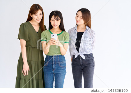 スマホの画面をのぞき込む3人の女友達 スマホの画面をのぞき込む3人の女友達 143836190