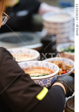 青花磁の器に盛られた温かい麺料理を提供する様子 青花磁の器に盛られた温かい麺料理を提供する様子 143838153