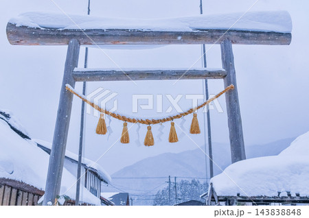 2月中旬の雪の型の大内宿で雪化粧した民家の屋根並みを背にしめ縄が飾られた高倉神社一之鳥居を望む冬風景 2月中旬の雪の型の大内宿で雪化粧した民家の屋根並みを背にしめ縄が飾られた高倉神社一之鳥居を望む冬風景 143838848